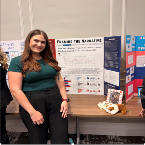 Baylor Sociology major, Christi Rodrigue, smiles next to poster showcasing her senior research project.